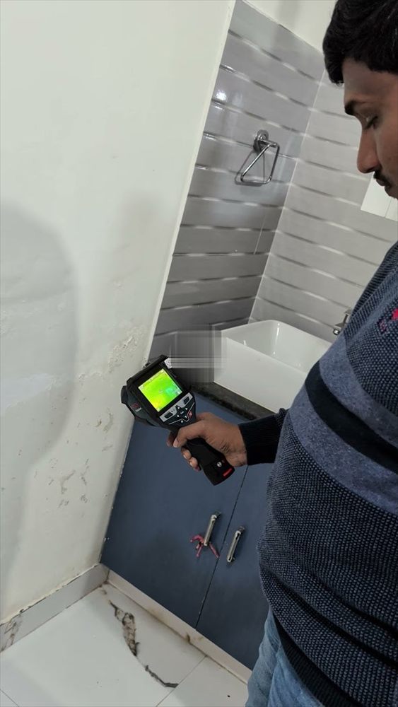 Technician inspecting a bathroom wall for a concealed leak
