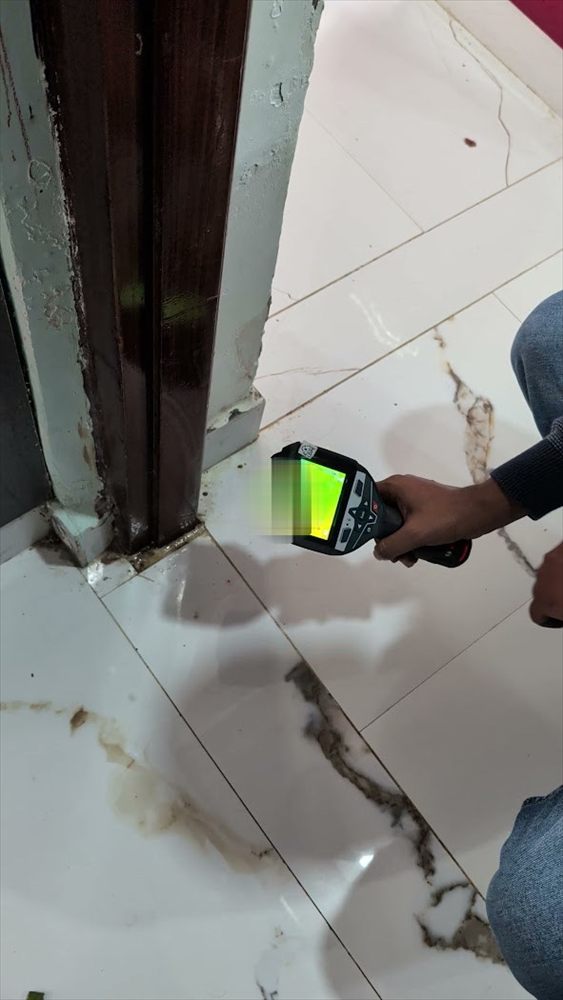 Technician locating a concealed leak near floor tiles